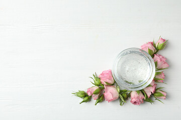 Flat lay composition with cosmetic gel and beautiful flowers on white wooden table. Space for text