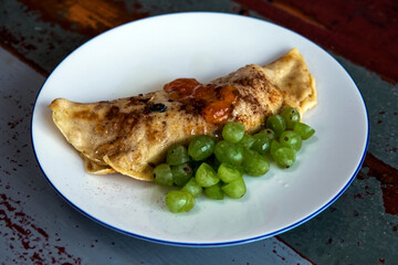 close-up of white plate with thin pancake and grapes