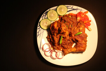 Masala Chicken, an Indian recipe, with lemon, fresh tomato, onion and green chilies, on a Banana leaf.