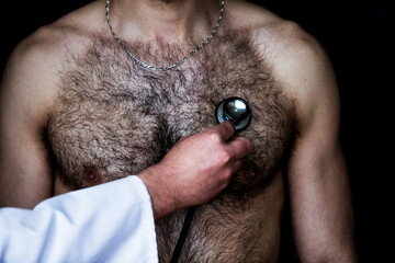 doctor with a stethoscope listening to a shirtless patients heartbeat