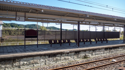 Empty platform with station sign and wooden seats in train station for background with copy space