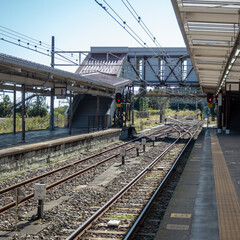 Empty platform with bridge over track at train station on clear blue sky background with copy space