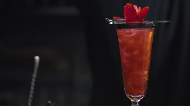 Ready-made Strawberry Rossini Cocktail rotating and slowly moving on slider. Close up bartenders hand sprinkling berry with powdered sugar. Bar drinks series.