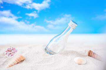 bottle on sand beach with seashell over blurred tropical blue sea and clear blue sky
