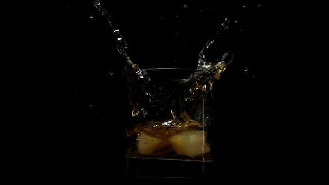 Ice cubes falling in glass with liquor, slow motion 500 fps