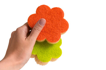 Sponges for washing dishes in a female hand on a white isolated background. Colored sponges in the shape of a flower.
