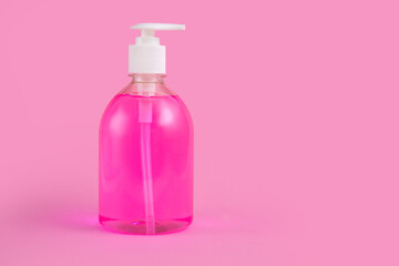 Bottle of pink liquid soap or dishwashing liquid on a pink background copy space.