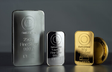 Silver and gold bars and coin on a dark background.