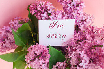 inscription I am sorry on a white gift card in a beautiful spring bouquet of lilac flowers 
