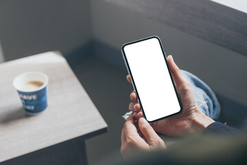 cell phone mockup image blank white screen.woman hand holding texting using mobile on desk at coffee shop.background empty space for advertise.work people contact marketing business,technology