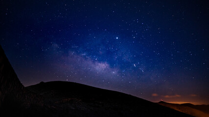 Panoramaufnahme des Sternhimmels mit Milchstraße über Hügellandschaft