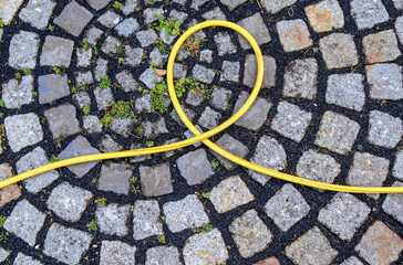 Top view of hosepipe on grass and cobblestone surfaces. Minimalistic conception
