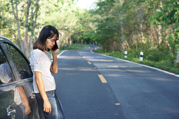 Asian woman Call a mechanic, the car goes out on the road around the forest.             