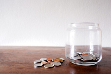Thai coins and the Glass jar on the wood table with white background for using as background, texing the message information.