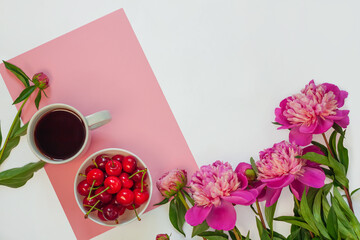 Still life with cup of coffee, sweet cherries and peony flowers on white background. Creative minimalism pink purple colors flat lay. Summer template for feminine blog, female social media copy space.