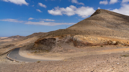 Kurvige Bergstraße führt durch Wüstenlandschaft um einen Berg herum