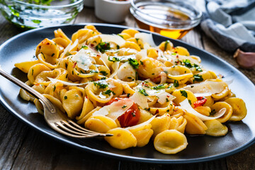 Pasta with parmesan and vegetables on wooden background
