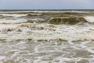 Dirty sea waves hitting the beach in stormy weather