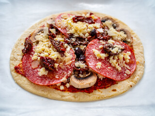 Uncooked margherita pizza on baking paper
