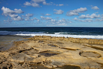 The rock pools in the sandstone shelf on the beach at Sliema, Malta.