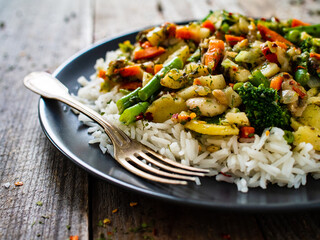 Roast meat, white rice and vegetables on wooden table
