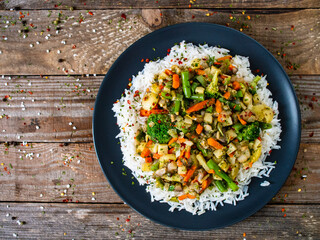 Roast meat, white rice and vegetables on wooden table
