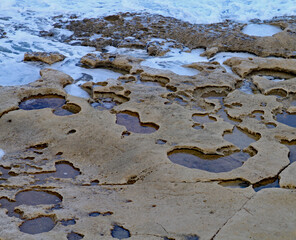 The rock pools in the sandstone shelf on the beach at Sliema, Malta.