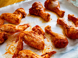 Raw chicken drumsticks and wings on baking paper