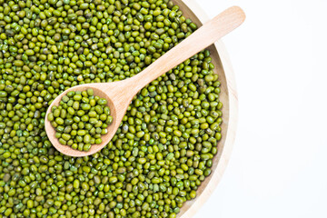 Raw fresh mung beans seed or organic green beans in a wooden bowl and wooden spoon isolated on the wooden plate table background.Healthy food ,Agriculture concept.Copy space.