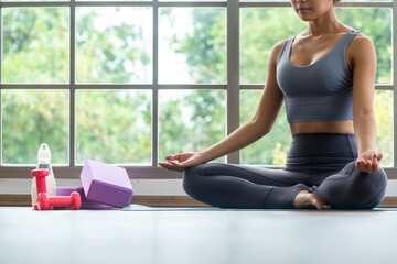 Equipment for practising yoga consist of mat, drumbel, block and wrist with woman preparing by meditating