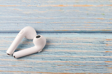 A white wireless headphone on wooden background.