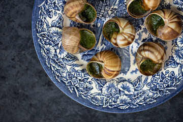 Snails with herbs butter served on beautiful blue vintage plate. Escargot de Bourgogne