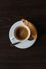 Coffee cup with cracker and spoon on limpet, dark background, vertical