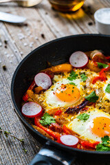 Shakshuka - fried eggs with vegetables in frying pan
