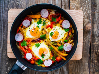Shakshuka - fried eggs with vegetables in frying pan
