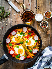 Shakshuka - fried eggs with vegetables in frying pan
