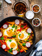 Shakshuka - fried eggs with vegetables in frying pan
