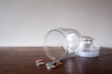 Thai coins and the Glass jar on the wood table with white background for using as background, texing the message information.