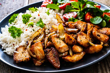 Chicken meat with rice and vegetables on wooden table
