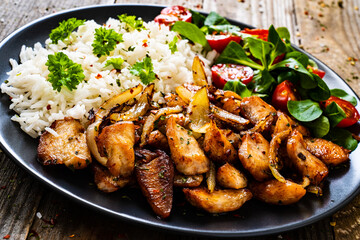 Chicken meat with rice and vegetables on wooden table
