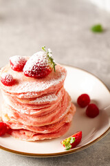 Stack of pink pancakes with strawberry. Pink colourful pancakes with berries. Breakfast