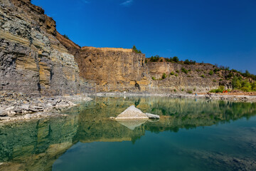 Fototapeta na wymiar Abandoned granite and sand quarry with a lake. Stone extraction in the canyon.