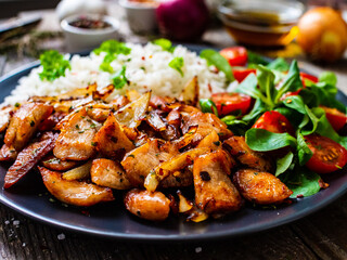 Chicken meat with rice and vegetables on wooden table
