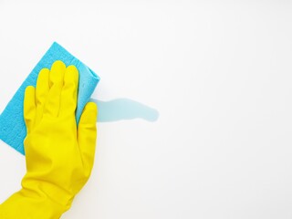Cleaning the blue liquid with a blue sponge in a yellow rubber glove on a white background. Space...