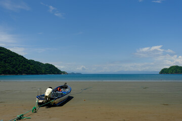 Tied down small Fishing boat on a wide expanse of empty beach on the Gulf of Nicoya in Costa Rica