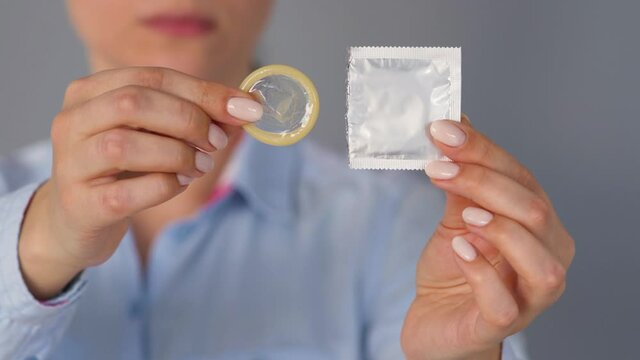 Female hands demonstrating condom before camera, safe sex, contraception