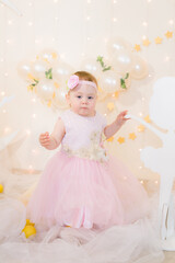 Cute little girl in a pink princess dress with a flower on her hair plays with wooden ballerinas...