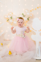 Cute little girl in a pink princess dress with a flower on her hair plays with wooden ballerinas...