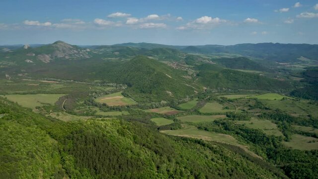 Aerial video flying over green meadows, forests and hills overgrown with lush vegetation in the spring time. The picturesque valley between hills of Eastern Balkan Mountains.