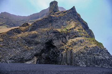Black sands and basalt cliffs and cave at low tide on Icelands Coast